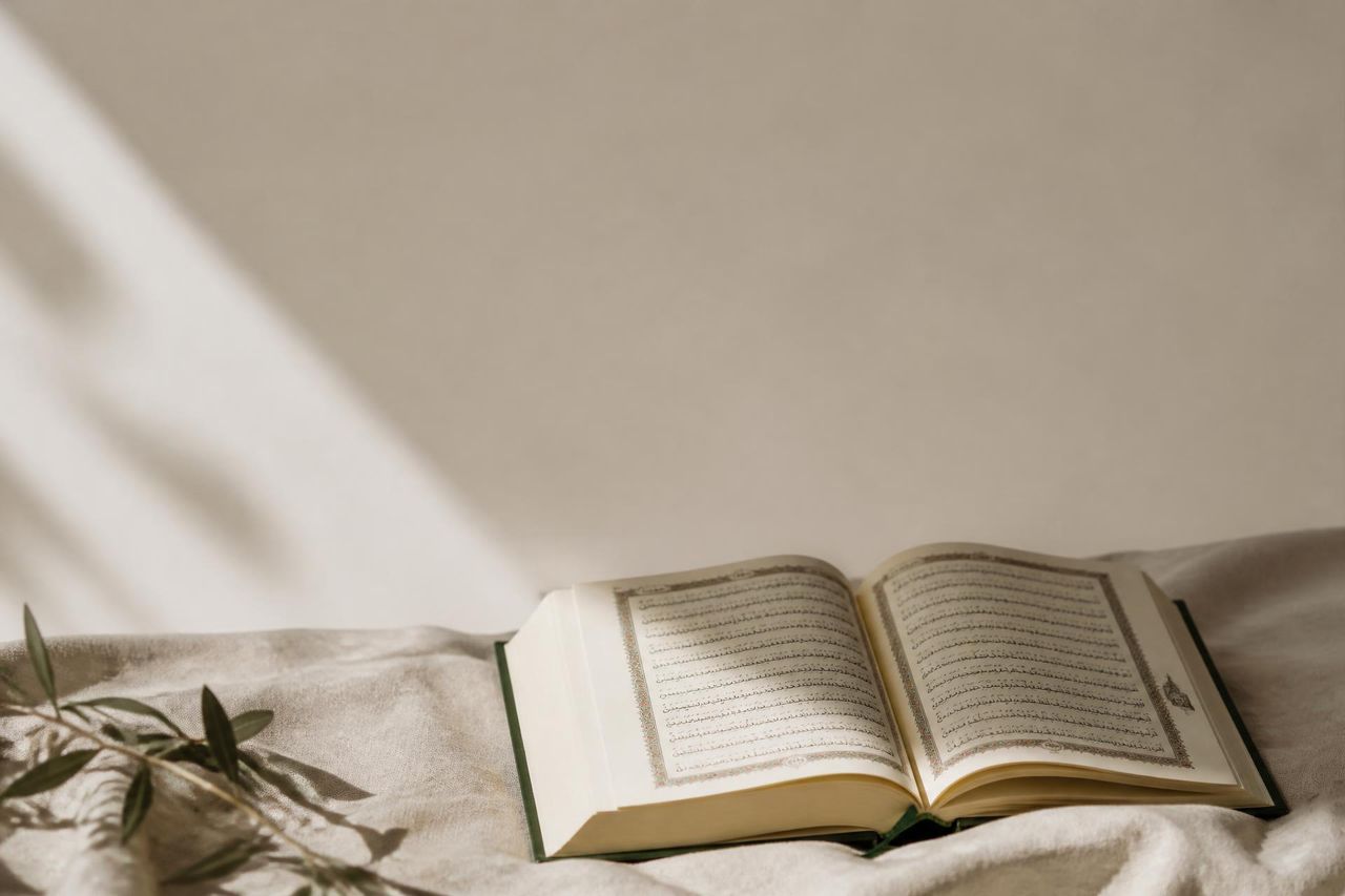 An open Qur'an resting on soft linen